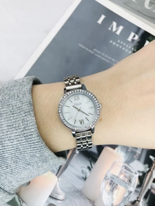 Close-up of women's silver steel watch with crystal bezel and white Roman numeral dial