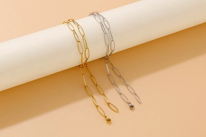 Detail of gold and silver paperclip link necklaces with lobster clasp on peach background