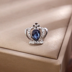 Dettaglio macro della spilla a corona argentata con cristallo blu e strass brillanti