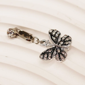 Vue macro du clip de nombril papillon argenté avec strass scintillants sur texture