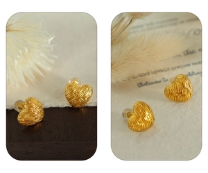 Detail of French vintage gold woven heart earrings on a natural decorative background