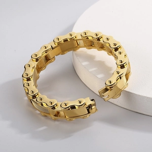 Golden watch chain style steel bracelet displayed on a white round stone pedestal