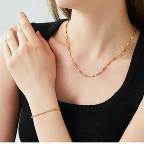 Model wearing a gold geometric rhombus link necklace and bracelet set in stainless steel