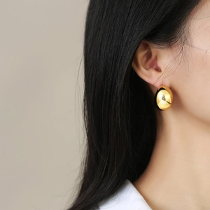 Close-up of elegant 18K gold hollow teardrop earrings showing polished mirror finish