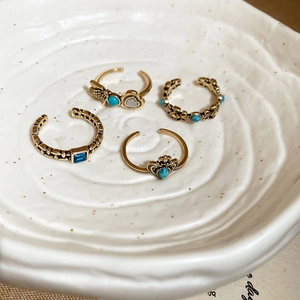 Detailed macro view of bohemian gold rings with turquoise stones and textured patterns