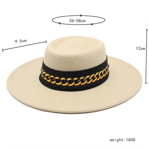 Detail view of stylish beige wool fedora with black ribbon and thick gold chain link