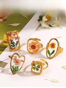Detail of 5-piece gold hammered rings with dried flowers in resin, set on a floral backdrop