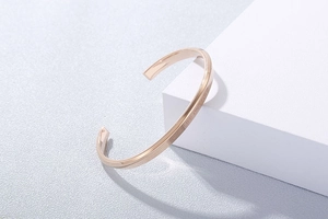 Detail of rose gold C-shaped cuff bracelet with ONE LIFE ONE LOVE engraving