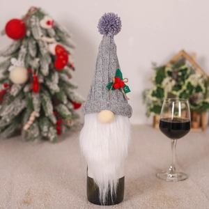 Detailed view of gray knitted gnome wine bottle cover with white beard and festive berries