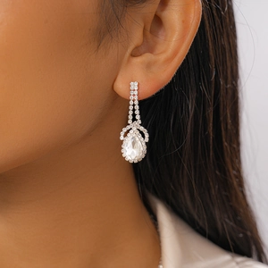 Close-up of a silver drop-shaped earring with sparkling rhinestones on model's ear