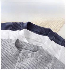 Detail of ribbed knit baby onesies showing soft texture and metal snap buttons