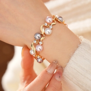 Détail d'un bracelet vintage doré avec perles roses et grises et strass étincelants