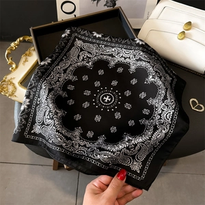 Detailansicht eines luxuriösen Seidensatinschals mit klassischen Paisley- und Kreuzmustern