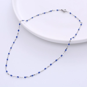 Silver titanium steel necklace with blue enamel lip-shaped charms on a white plate