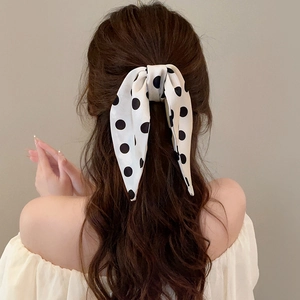 Close-up of black and white polka dot silk hair bow tie on woman half-up hairstyle