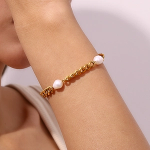 Golden stainless steel Cuban link bracelet with three elegant white pearls on model wrist