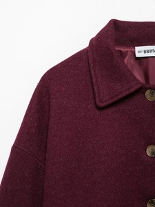 Macro detail of dark red wool coat collar with brown button and thick textured fabric