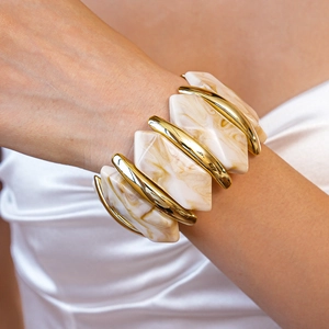 Détail d'un large bracelet en résine acrylique marbrée avec accents dorés