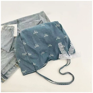 Close-up of blue denim bandana with white bow patterns and elegant white lace trim detail