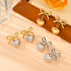Titanium steel bow and heart earrings set in gold and silver finishes on elegant backdrop