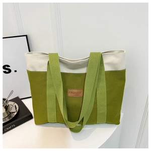 Detail of olive green and beige canvas tote bag with brown leather fashion logo patch