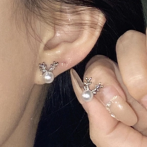 Detail of silver reindeer earrings with white pearl accent worn on ear in forest style