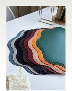 Stacked colorful faux leather table mats with unique scalloped edges in eight vibrant tones