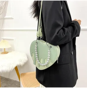 Detail of light green heart bag with unique liquid-drip texture and silver bead handle