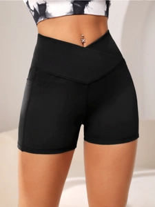 Detail of high-waist crossover yoga shorts with side pocket in black moisture-wicking fabric