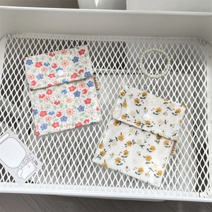 Detailed view of floral cotton storage bags with snap buttons and woven labels