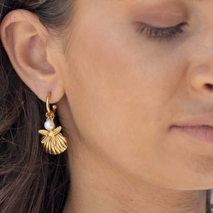 Detail of gold-plated hoop earring with pearl and seashell charms on model