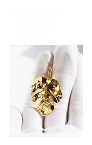 Detailed view of gold monstera leaf earrings with a hammered metal finish and cutouts