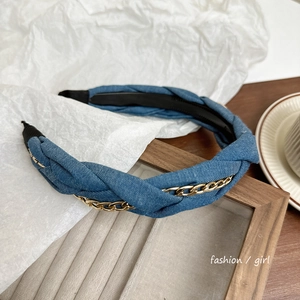 Detailed macro view of denim blue fabric headband braided with a golden metal chain link