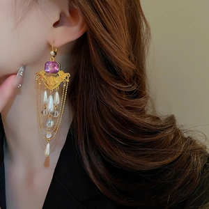 Gros plan de boucles d'oreilles vintage à pampilles avec perles et gemme violette