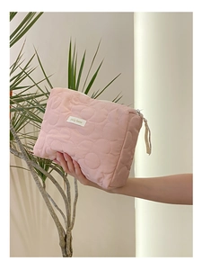 Vue détaillée de la trousse de toilette rose matelassée avec des coutures à motifs de fleurs