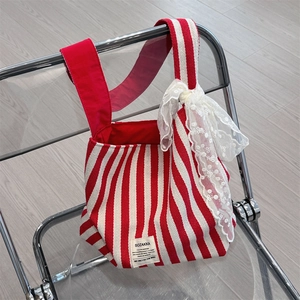 Close-up of a red and white striped canvas tote bag with a decorative lace bow detail
