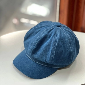 Close-up of vintage dark blue denim newsboy cap showing texture and stitching detail