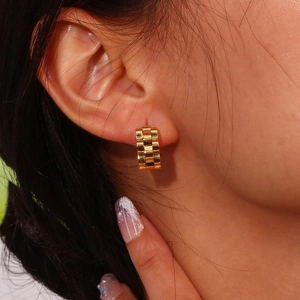 Close-up of golden watchband style chain link earrings on model with high gloss finish