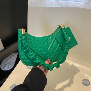 Detail of emerald green quilted crescent bag with ruched strap and matching mini pouch