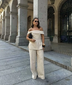 Close-up of off-shoulder beige knit top and matching wide-leg trousers in linen texture