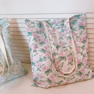 Detail of floral canvas tote bag with pink rose patterns and stitched woven label