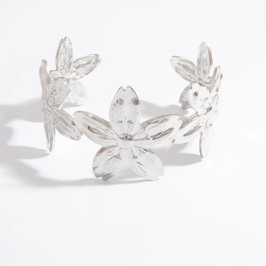 Macro shot of silver titanium steel open bangle with detailed cherry blossom floral design