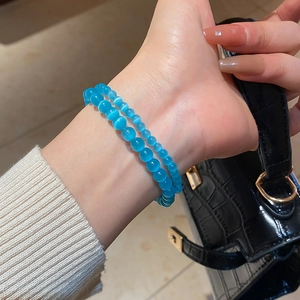 Close-up of dual-layer blue cat-eye beaded bracelets on wrist with 8mm and 4mm beads