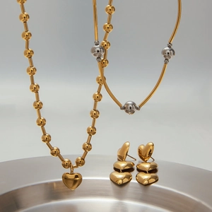 Gros plan d'un ensemble collier et boucles d'oreilles cœur doré sur plateau argenté