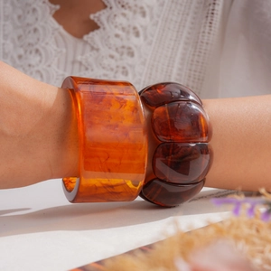 Detailed view of stylish marbled orange and dark amber acrylic resin bracelets on a wrist