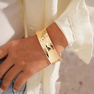 Detail of wide gold-finish geometric open cuff bracelet with high-shine mirror surface