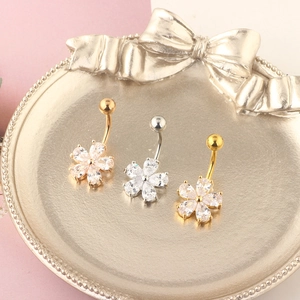 Detailed view of three flower belly rings in rose gold, silver and gold with zircons