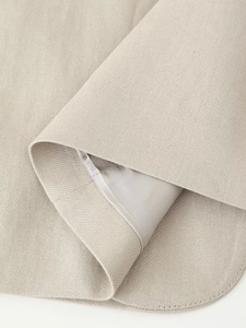Detail of beige woven fabric texture and smooth lining on sleeveless top hemline