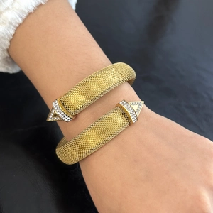 Detailed close-up of 18K gold mesh wrap bracelet with rhinestone triangle tips