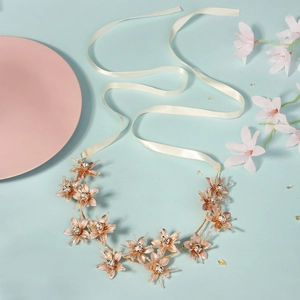 Detail of rose gold metal leaf headband with sparkling crystals and white ribbons